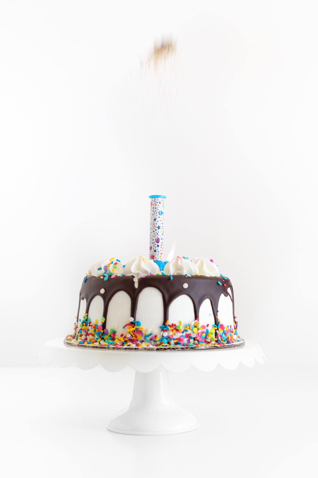 edible confetti popping out of a party popper candle on a birthday cake