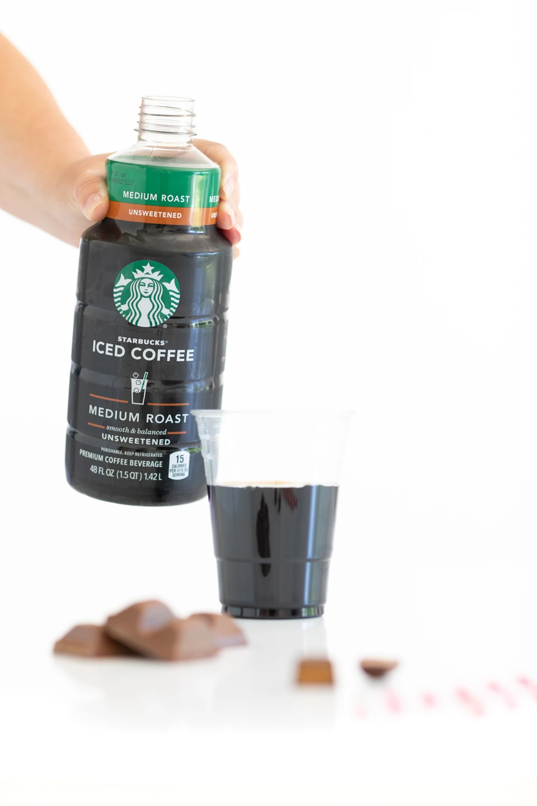 pouring a glass of starbucks iced coffee into a cup