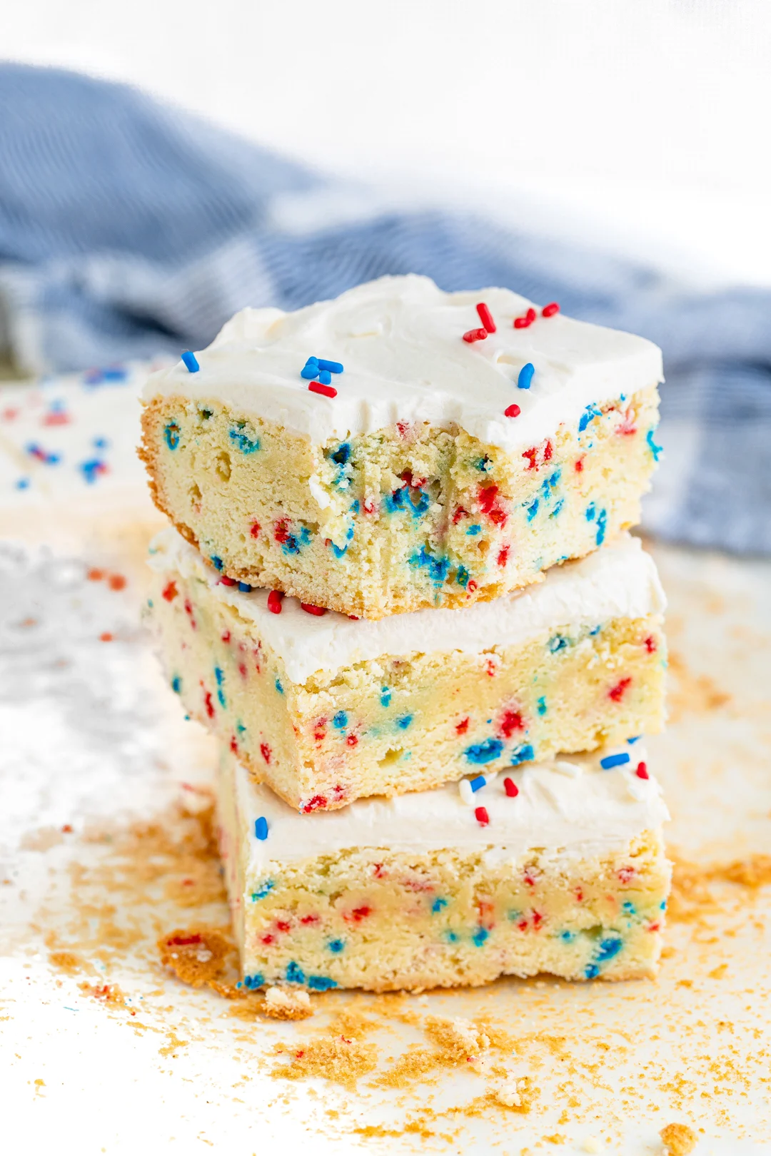 stack of three sugar cookie bars with red white and blue sprinkles on them with the top bar having a bite taken out of it.