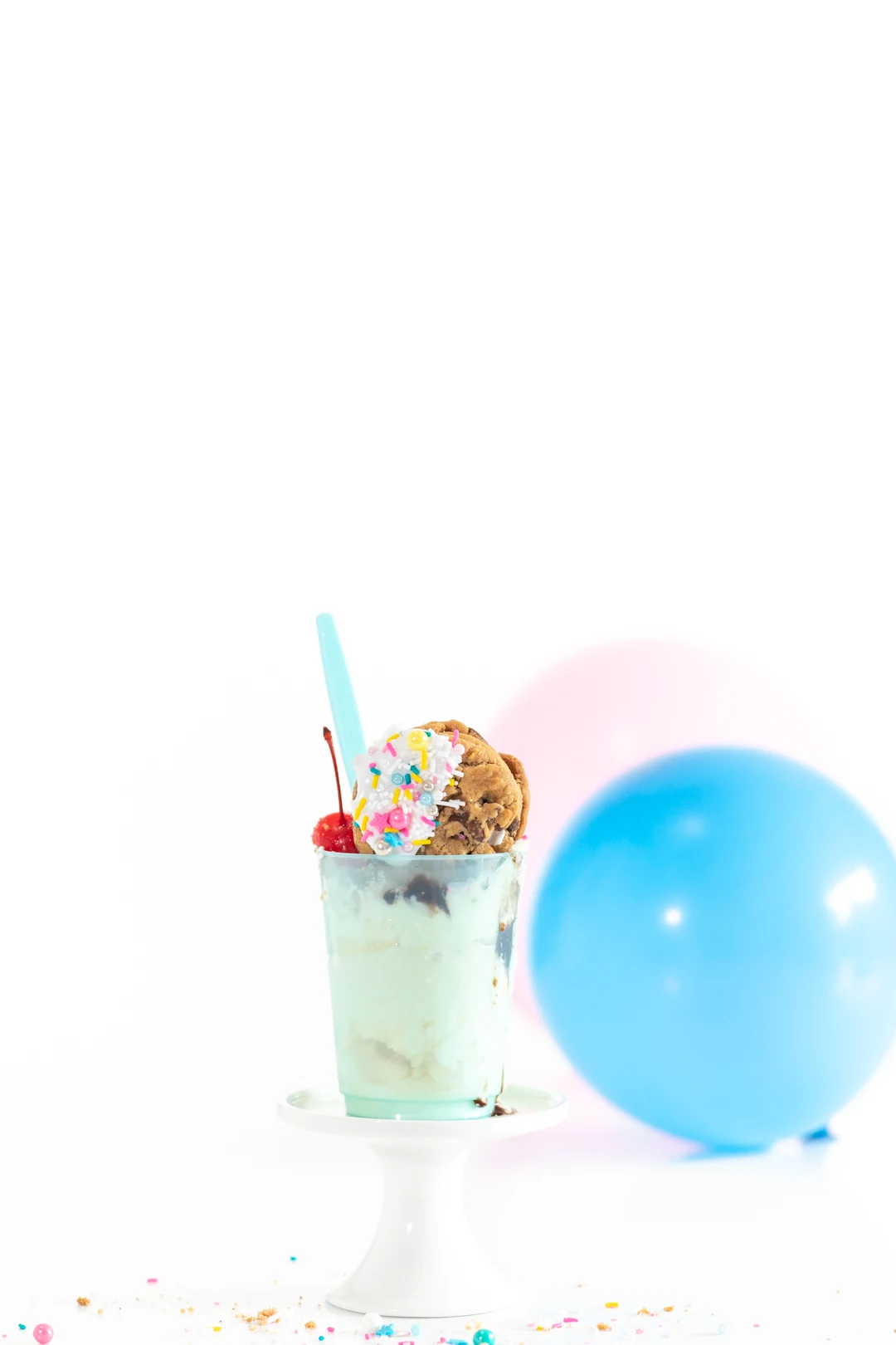 ice cream sundae served in a cute blue cup topped with a iced chocolate chip cookie pinata with sprinkles inseide