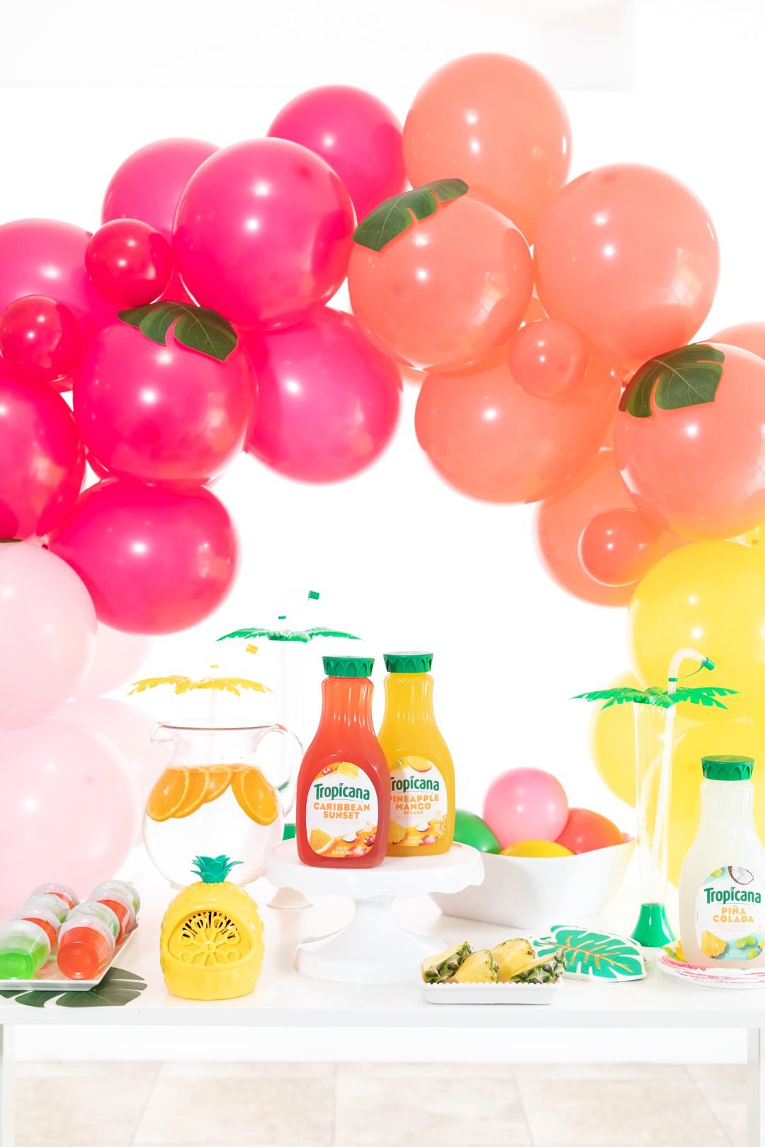 tropical refreshment table decorated with fun balloon garland with tropical inspired juice flavors