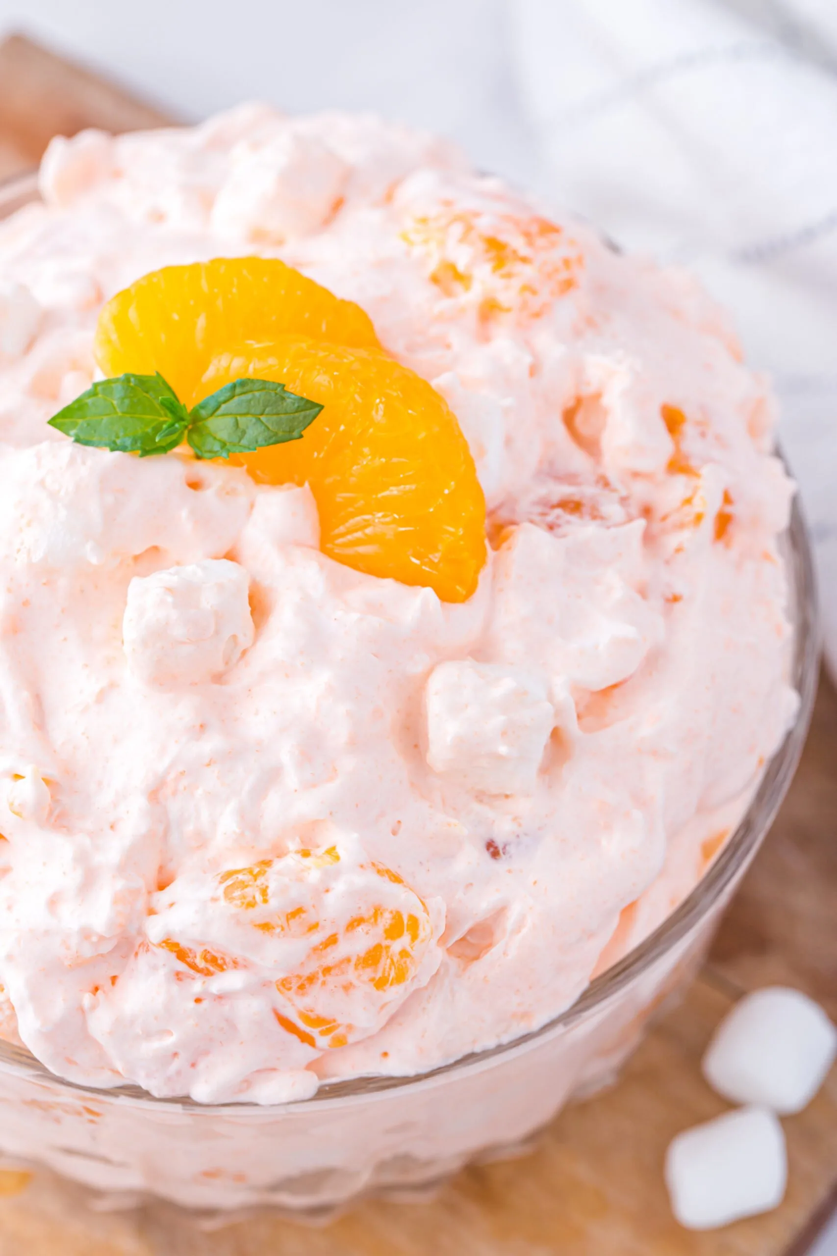 fluffy orange dessert made with whipped topping and canned mandarin orange. Topped with slice of mandarin orange and fresh mint sprig.