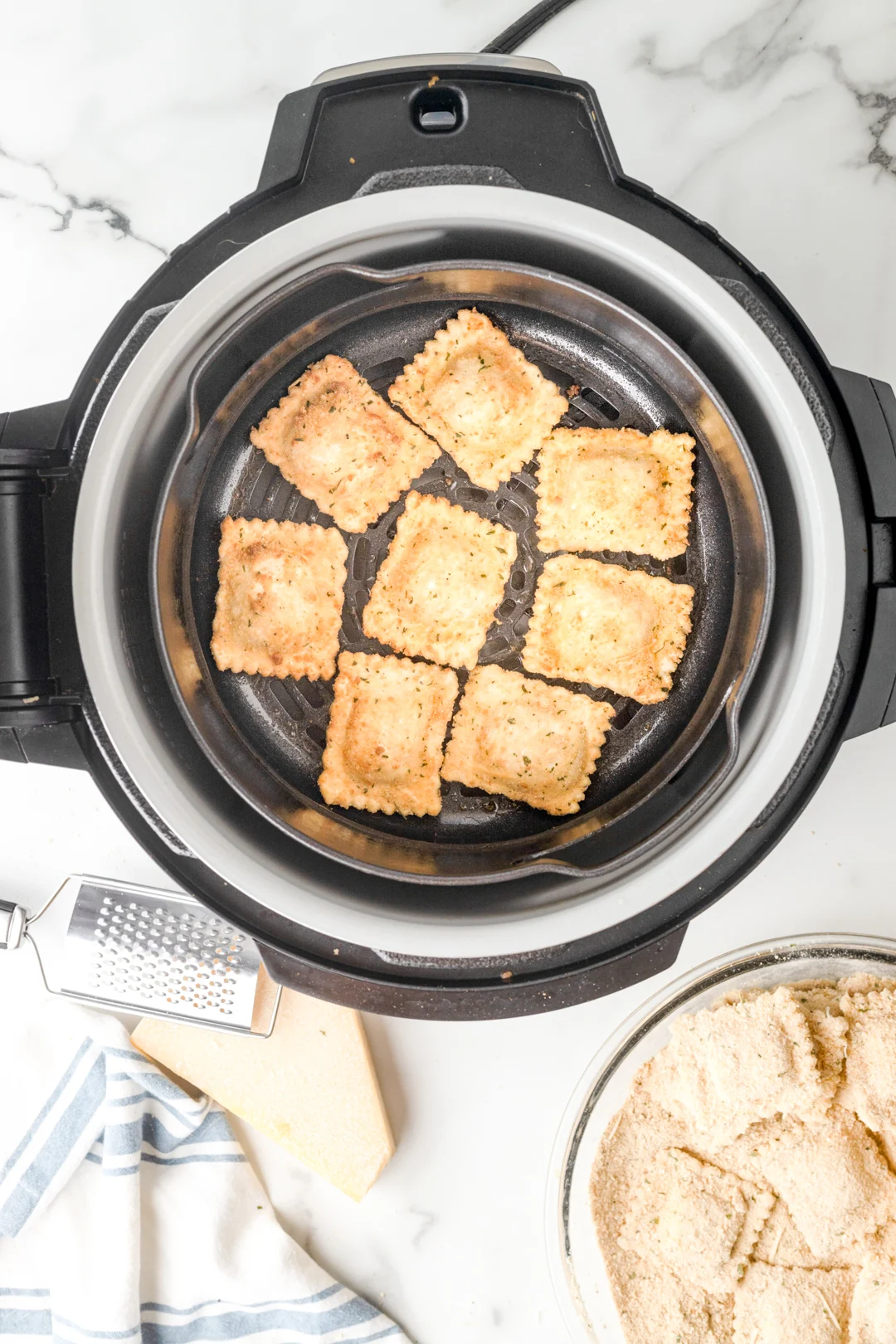 breaded ravioli inside of the air fryer getting ready to cook