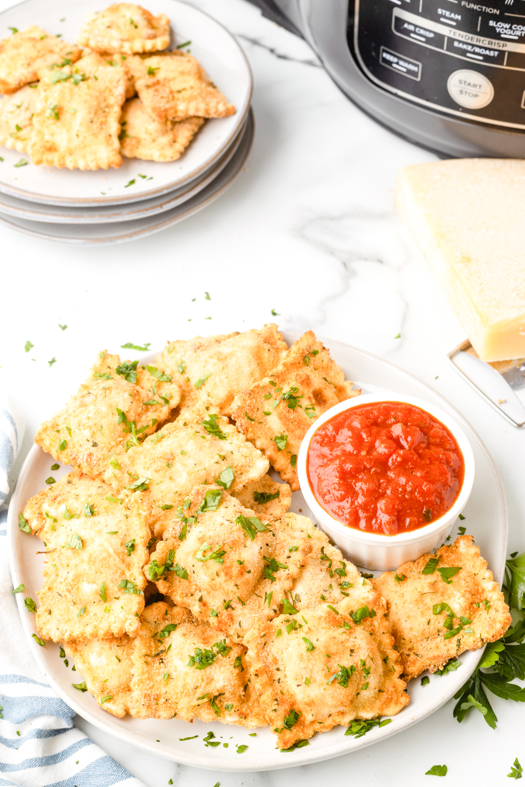 breaded ravioli appetizer on a plate with a small dish of marinara sauce for dipping