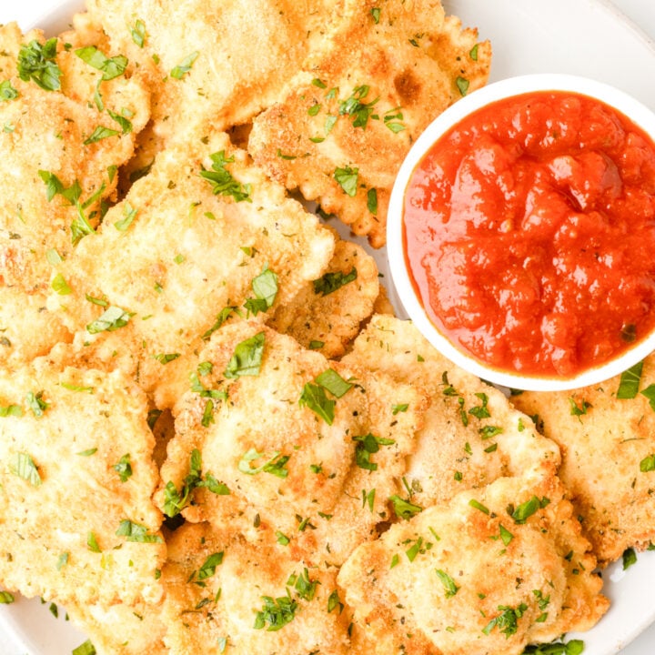 close up photo of plate of air fryer ravioli served with a small dish of marinara sauce