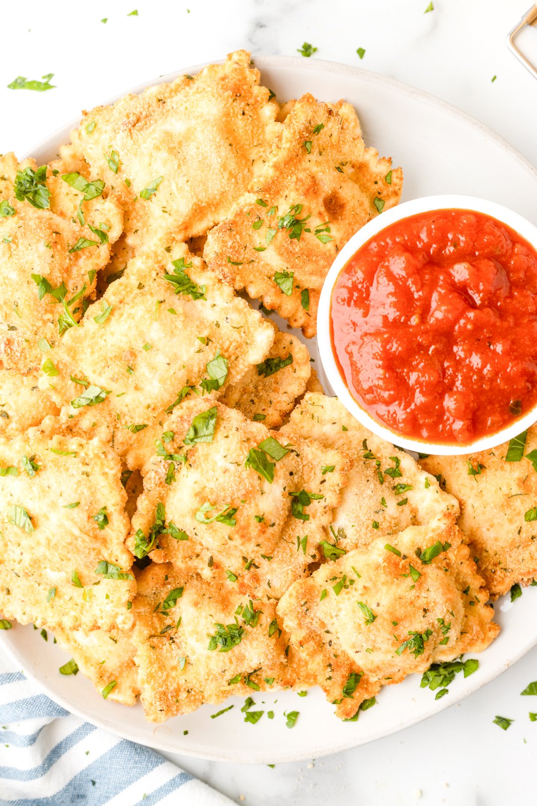 close up photo of plate of air fryer ravioli served with a small dish of marinara sauce