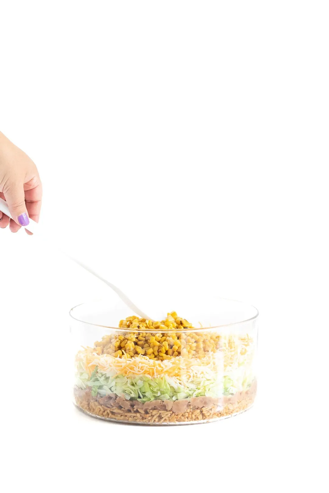 adding a layer of canned corn onto a mexican salad
