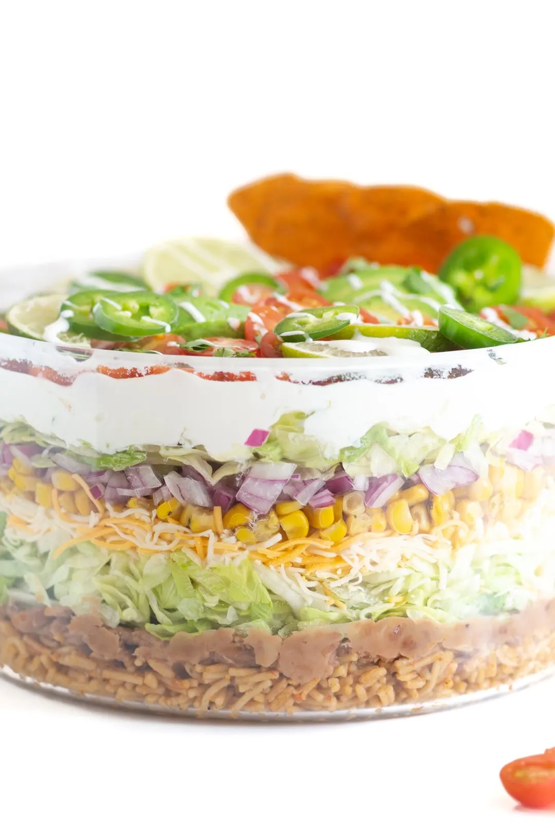 layered Mexican salad with refried beans, shredded lettuce, shredded cheese, diced onions, sour cream, canned corn. 