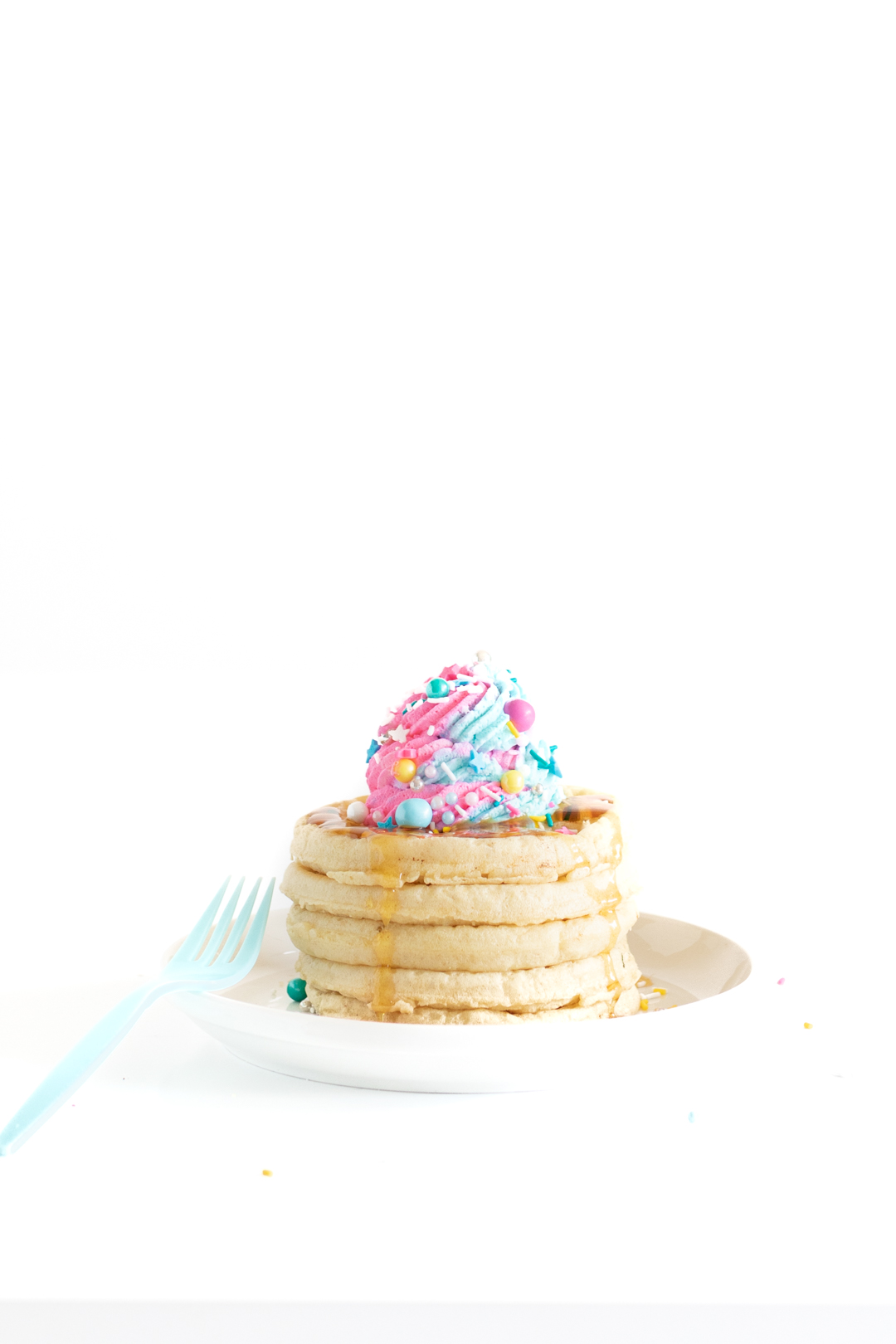 stack of 5 frozen waffles, toasted and topped with swirl of pastel whipped cream and matching sprinkles