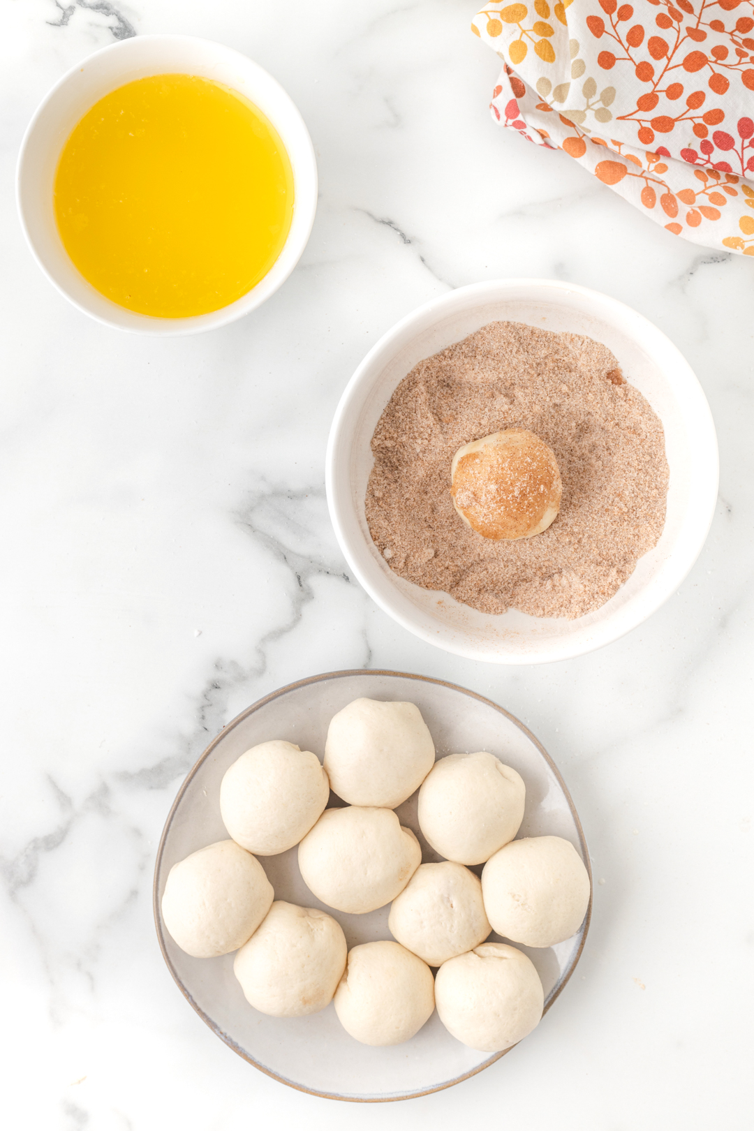 plate of dough balls getting ready to roll into spiced sugar mix