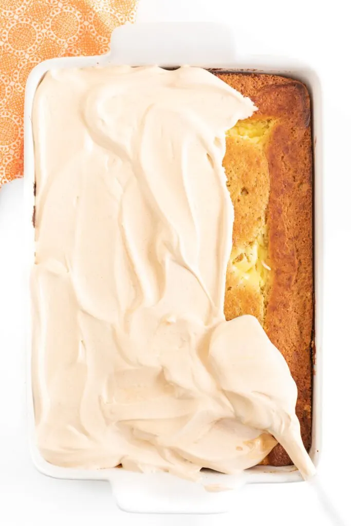 overhead photo of pumpkin cake being frosted with pumpkin spice pudding mixed with cool whip