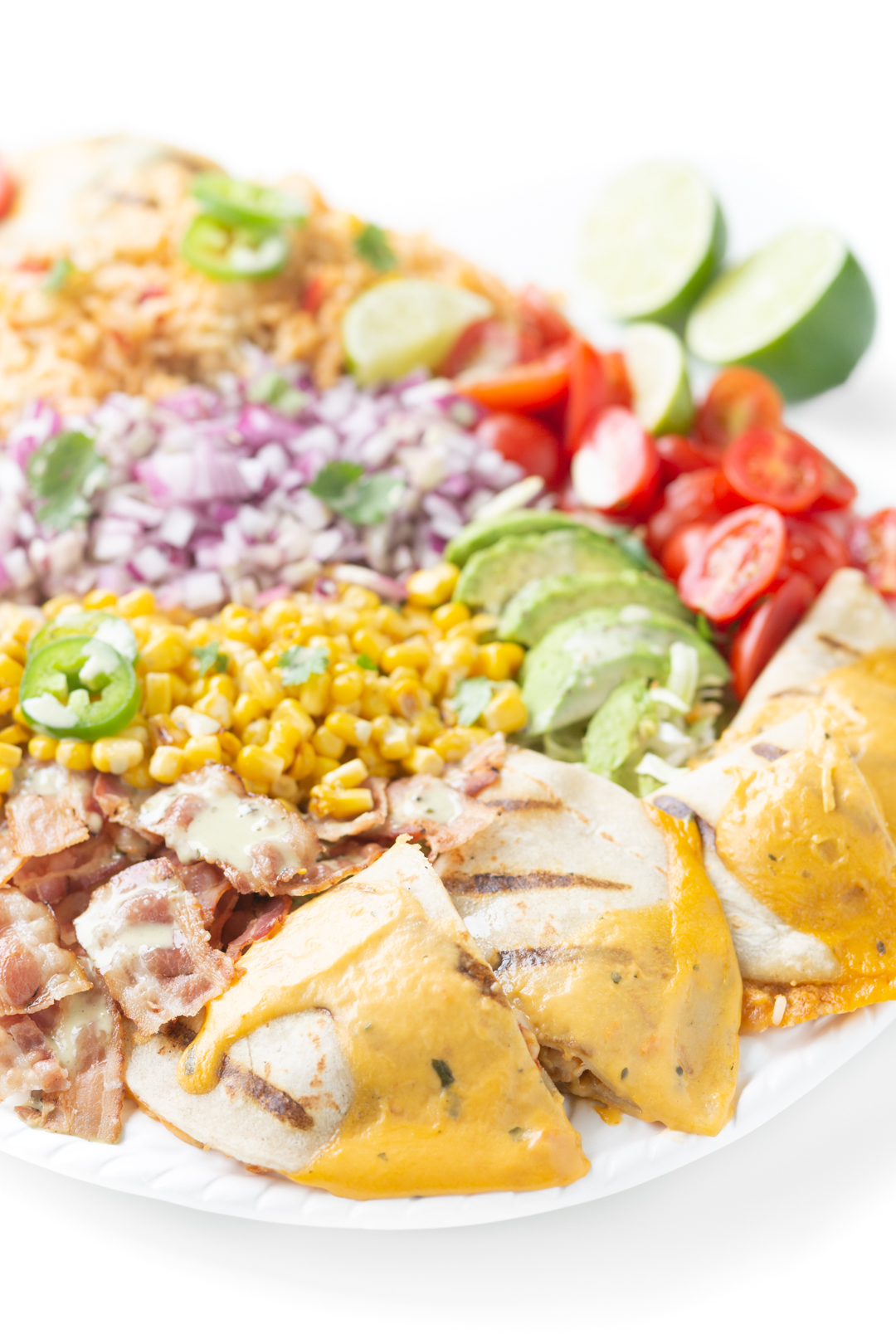 mexican inspired salad tray with mexican rice, quesadillas with cheesy sauce, bacon, grape tomatoes, fresh avocado slices, diced onions