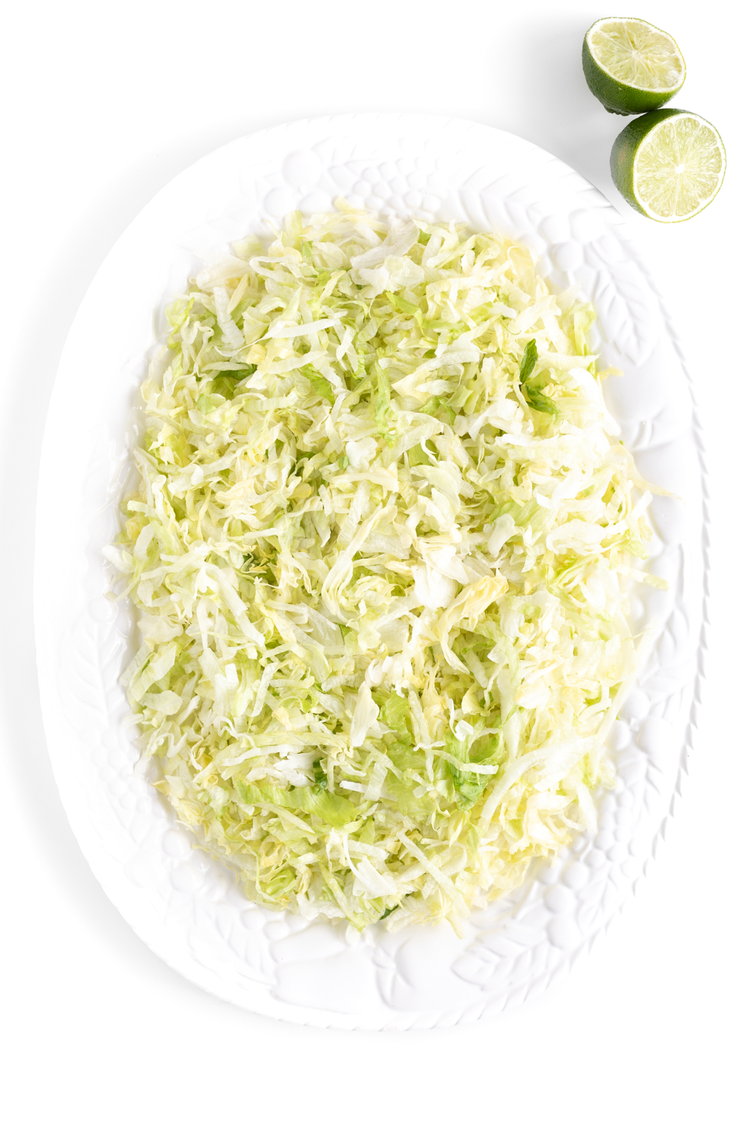 large serving platter with shredded lettuce in preparation of making a full salad.