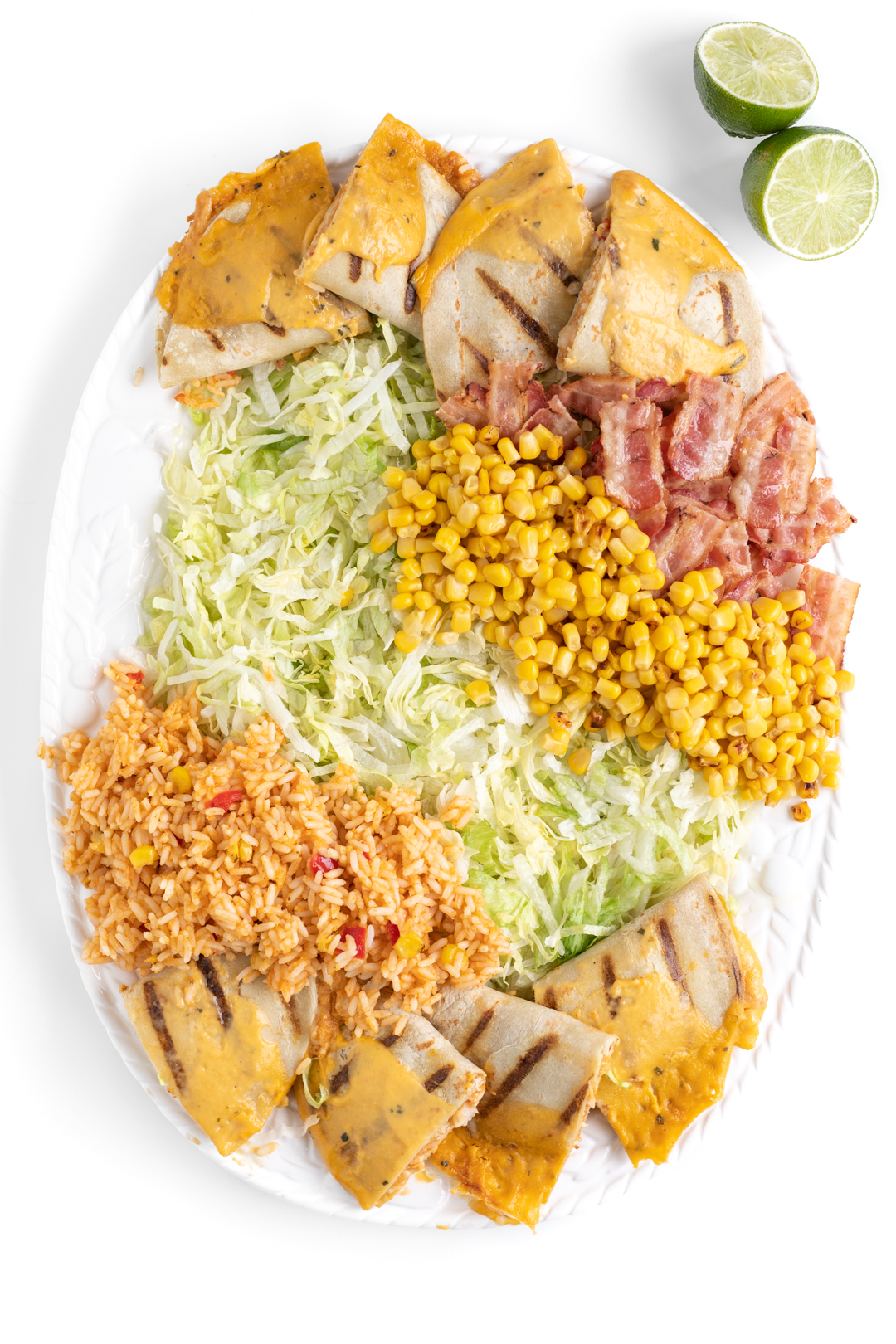 family sized salad being put together on a large tray with shredded lettuce, rice, corn, bacon.