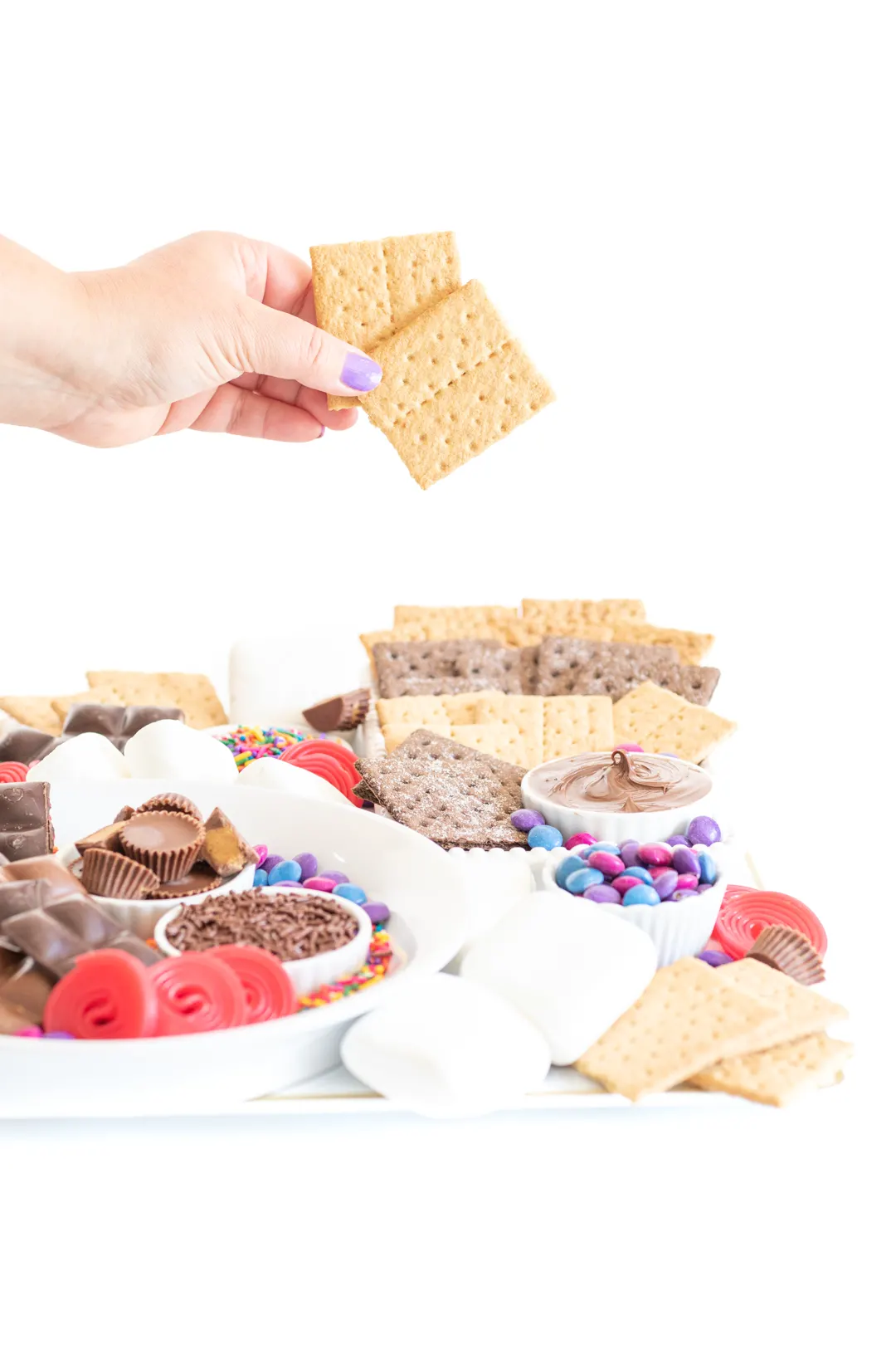 setting up a s'mores dessert board with graham crackers, candies and chocolate