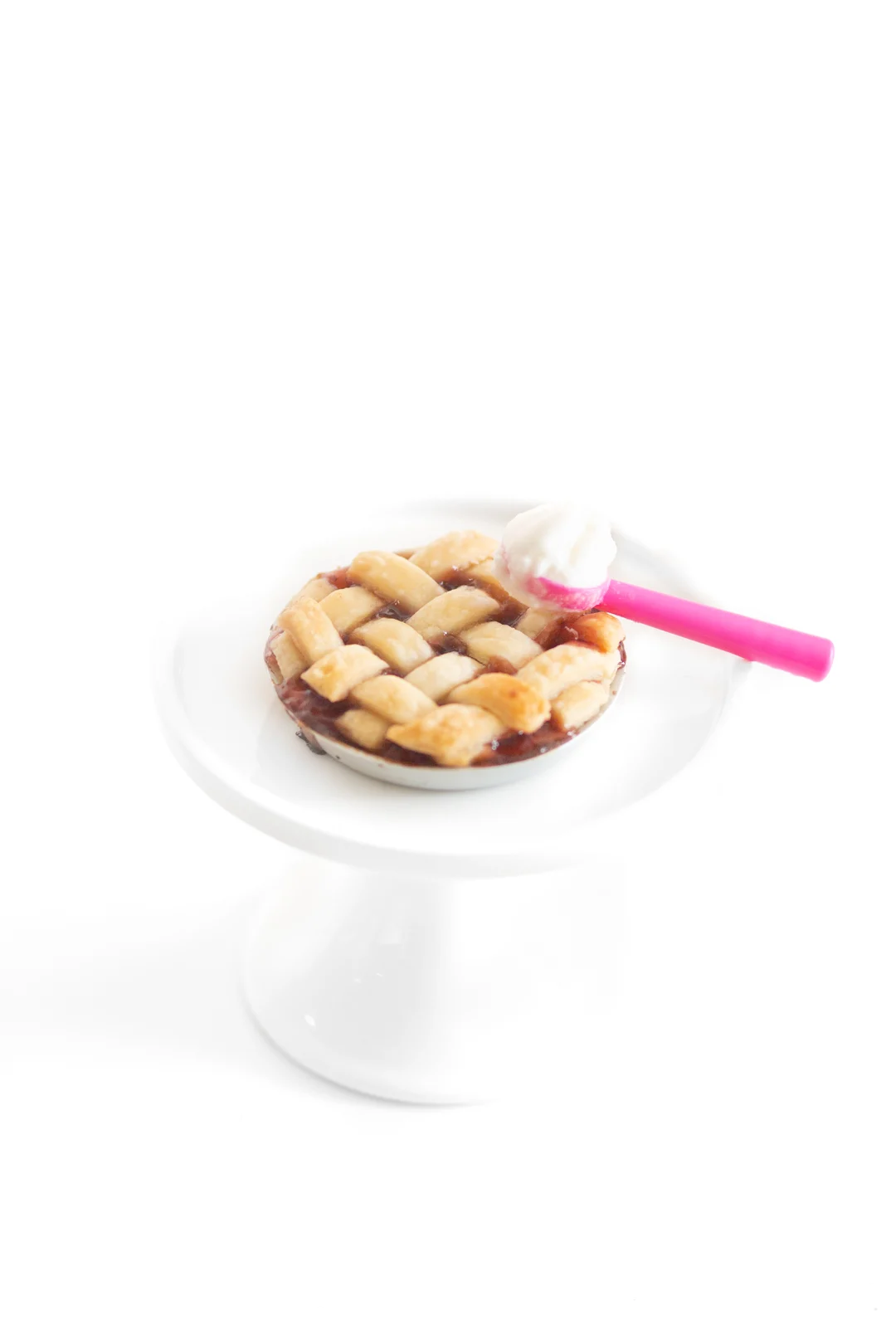 tiny lattice pie on a mini pedestal with a tiny pink ice cream scooper with vanilla ice cream on it