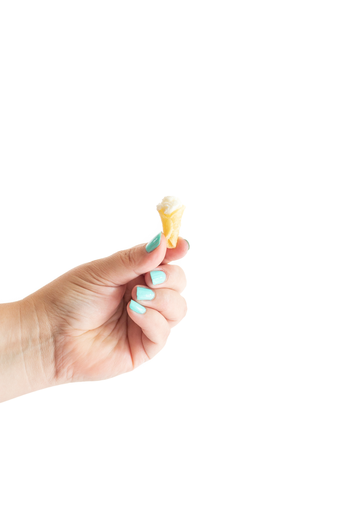 woman holding a tiny ice cream cone with a scoop of tiny vanilla ice cream in it