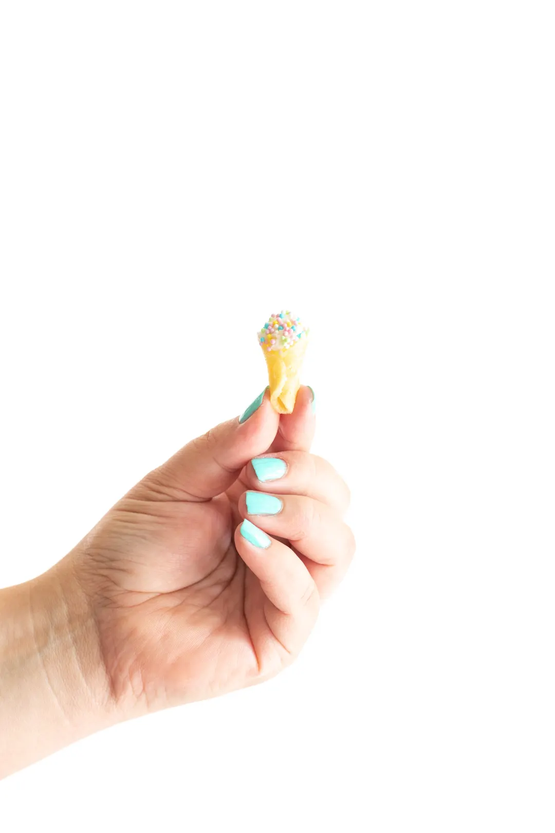 tiniest ice cream cone with sprinkles being held by woman with teal fingernails