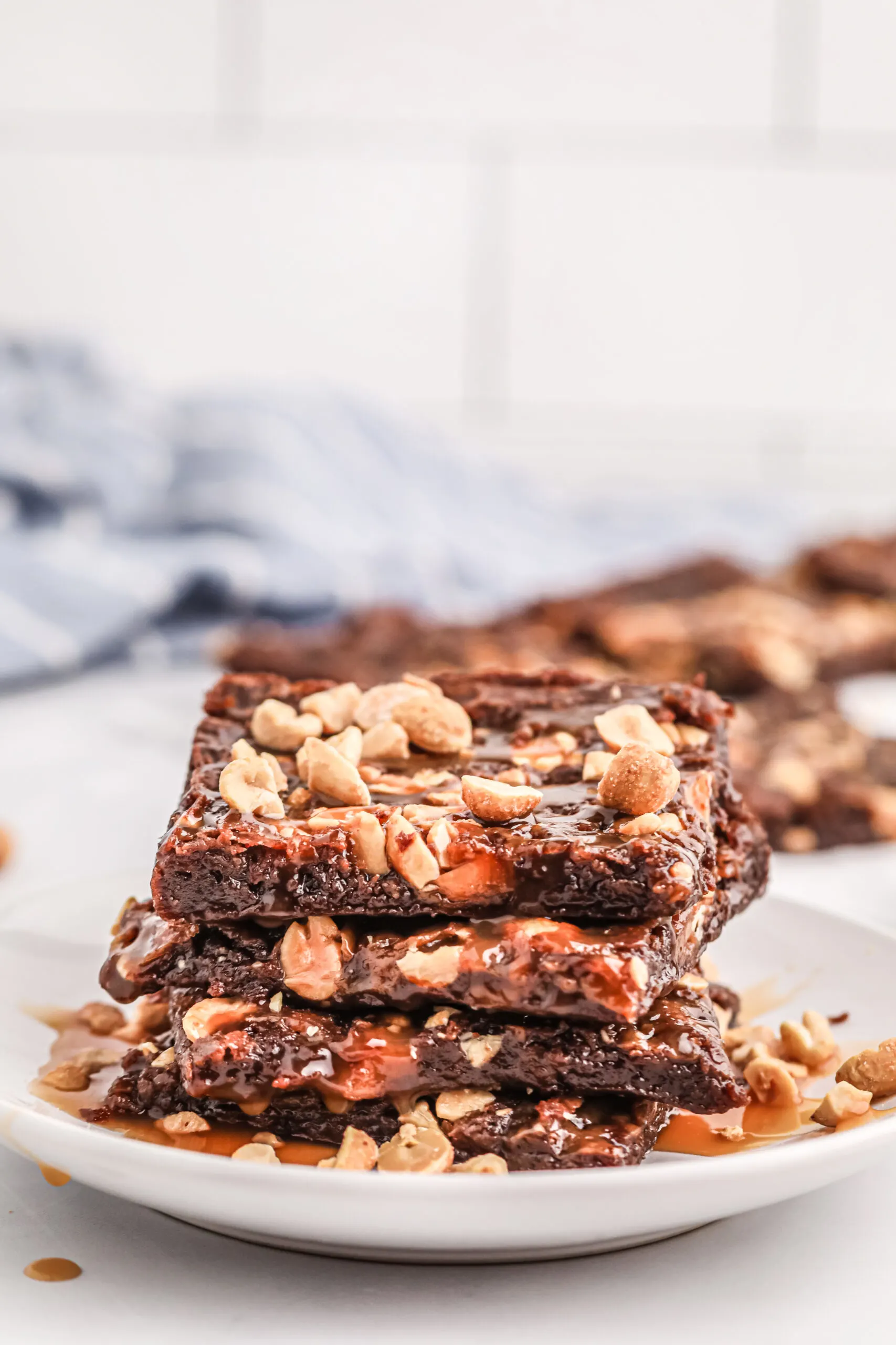 stack of thin, peanut topped brownies on a plate