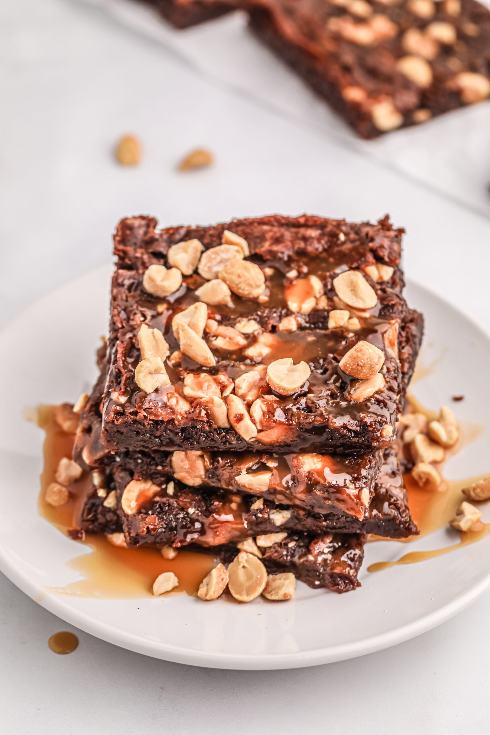 up close downward view of thin snickers brownies on a small white plate.