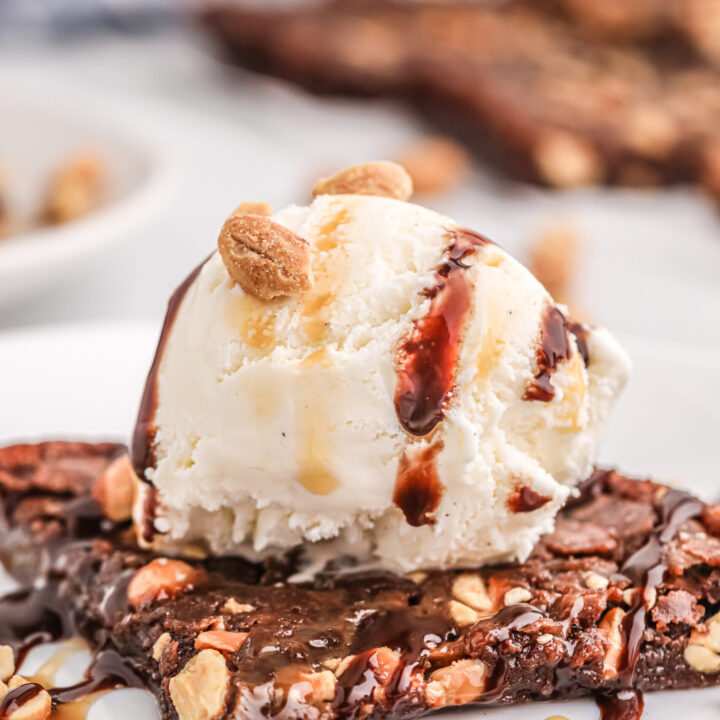 super up close view of thin brownie topped with ice cream scoop and chocolate and caramel drizzle