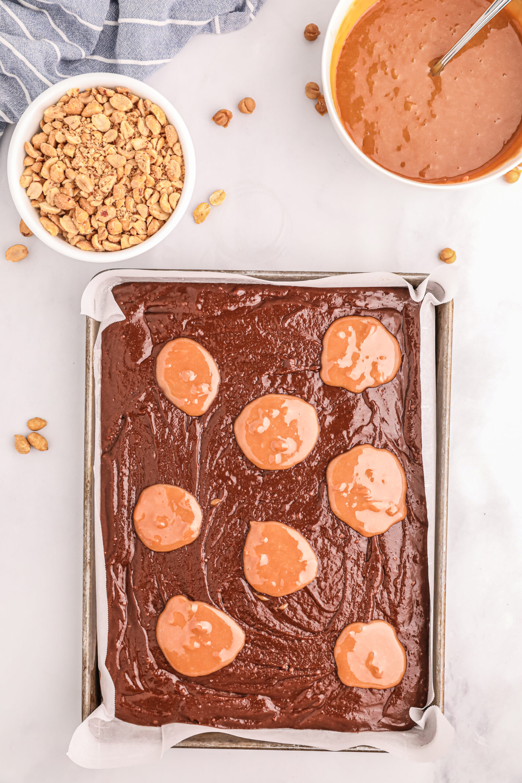 adding melted caramel bites to sheet pan brownie mix to swirl in