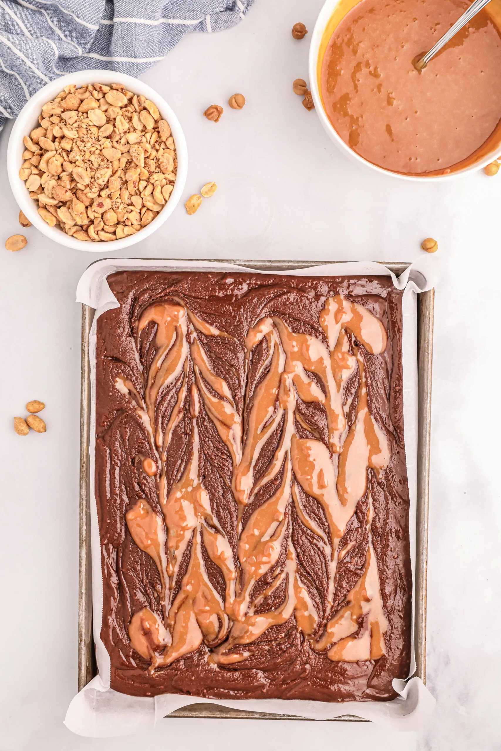 melted caramel bits swirled into brownie mixture in a baking sheet
