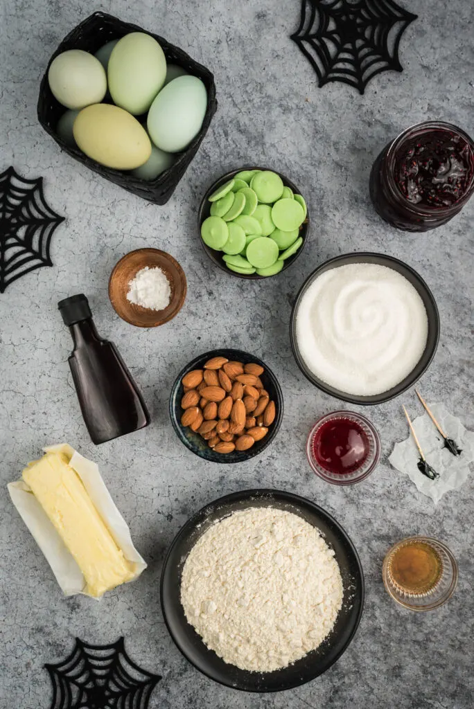 halloween witch cookie ingredient flat lay including black food coloring, butter, sugar, almonds