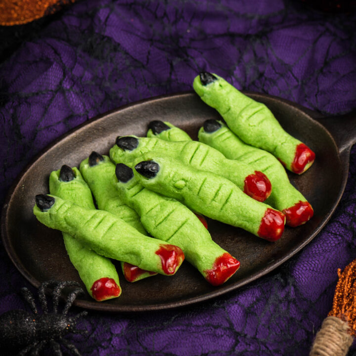 black platter of witch finger cookies with blood colored icing on the bottoms