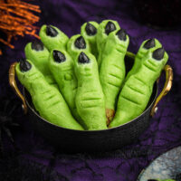 up close of witch finger cookies. green finger like cookies with black almond fingernails