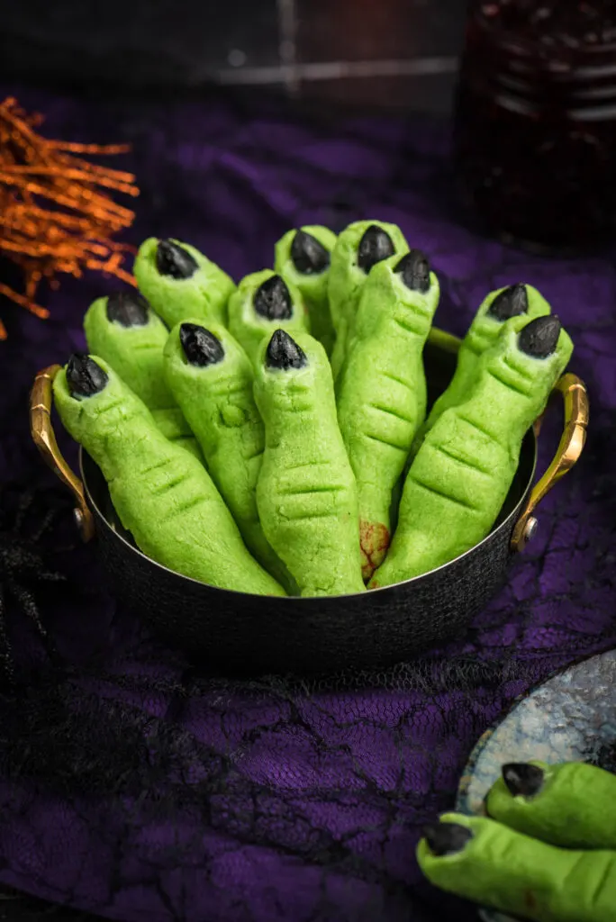up close of witch finger cookies. green finger like cookies with black almond fingernails
