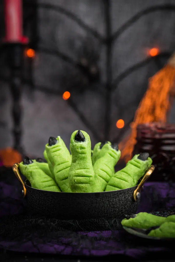 black cauldron filled with witch finger cookies in a halloween party setting