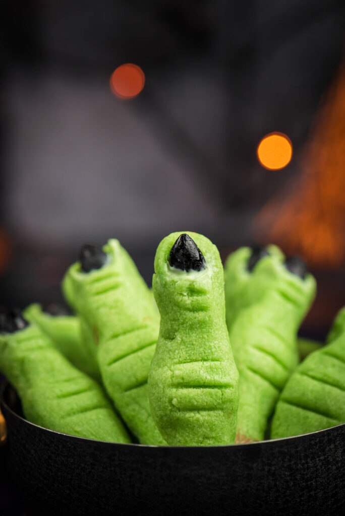green witch finger cookies with black fingernails in a spooky dark halloween setting