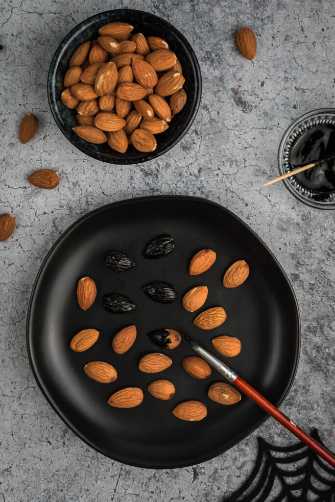 Using black food coloring to tint almonds to use as witch fingernails