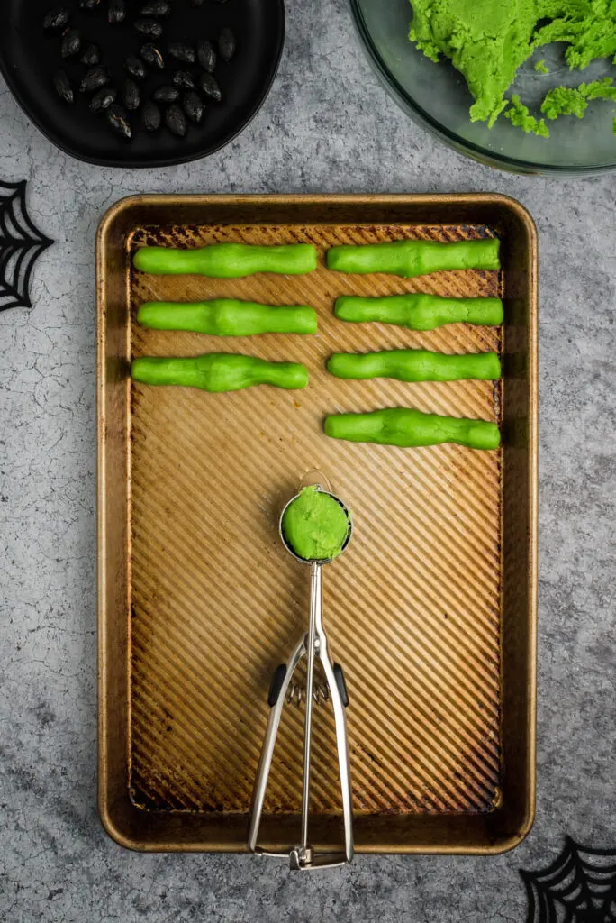 measuring out green sugar cookie dough to prepare witch finger cookies