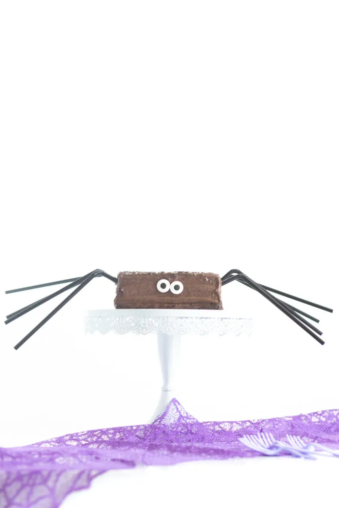funny halloween spider cake with black straws for legs and large candy eyes