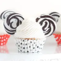 up close view of mickey mouse cupcake with vanilla buttercream, lollipops for ears and black polkadot cupcake liners