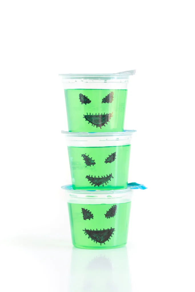 stack of three green gelatin cups, decorated for halloween