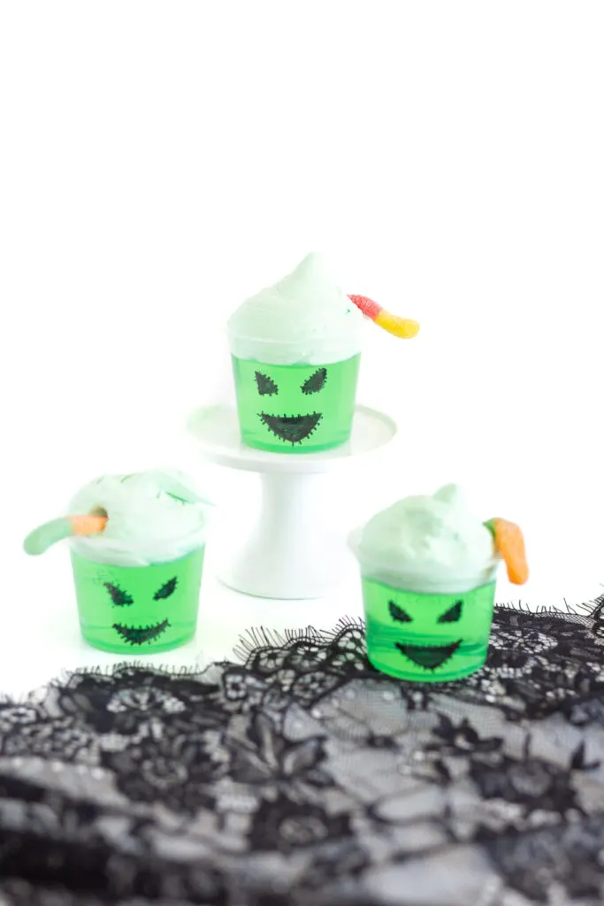 Oogie boogie jello cups using green jello, black sharpie to draw face on, green tinted cool whip and sour worms to decorate