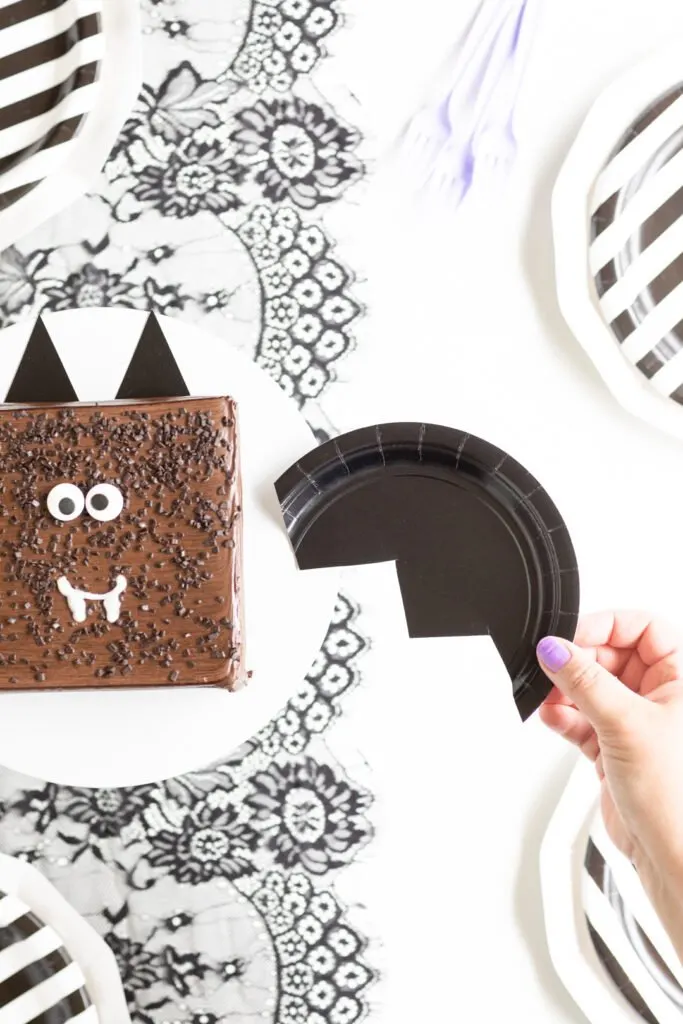placing a craft bag wing onto a bat themed cake