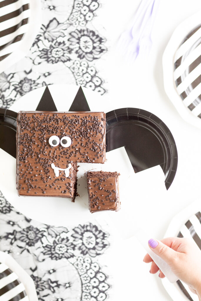 small chocolate bat themed cake with a square slice cut out of it