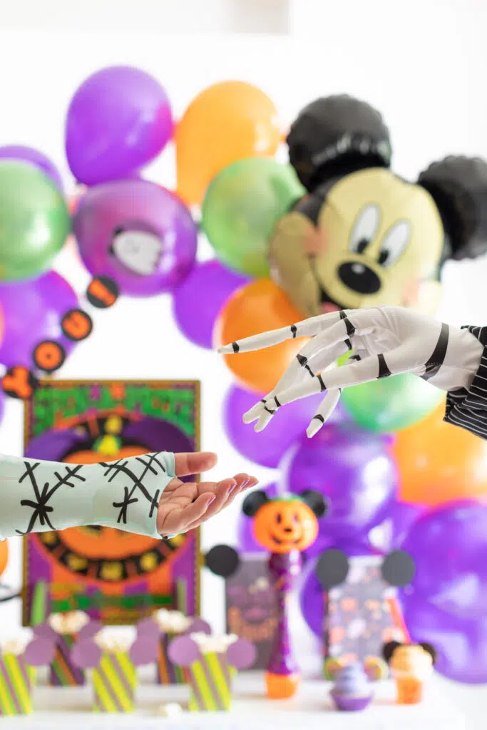 jack and sally about to hold hands in front of a mickey mouse halloween party table