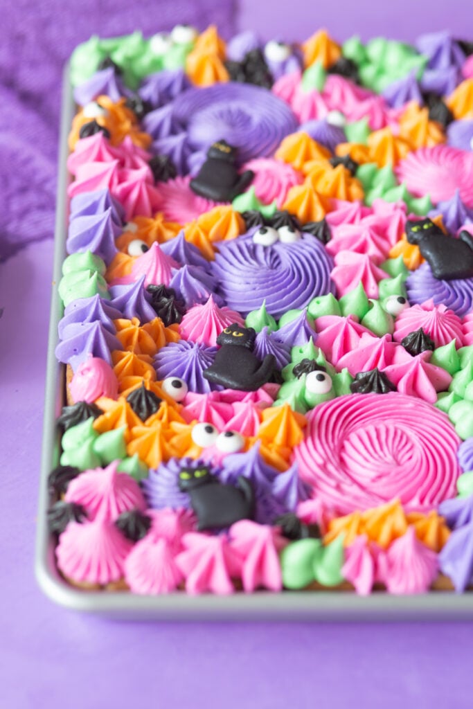 close up view of sheet pan cookies loaded with colorful buttercream frosting using different piping tips