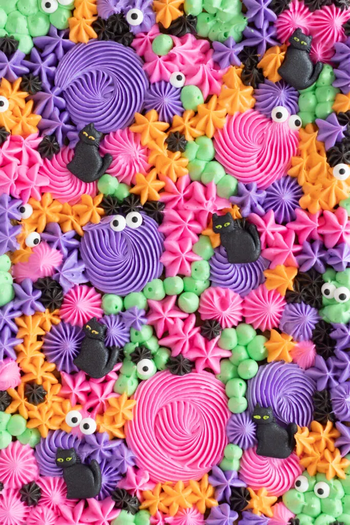 cropped in view of only frosting decorations from on top of a sheet pan cake. Cat icing decorations, small candy eyes.