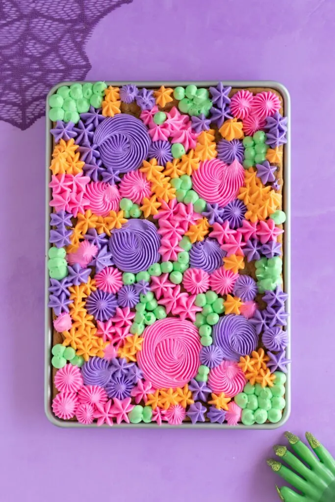 orange, purple, pink and green buttercream decorations on a half sheet pan of cookie bars