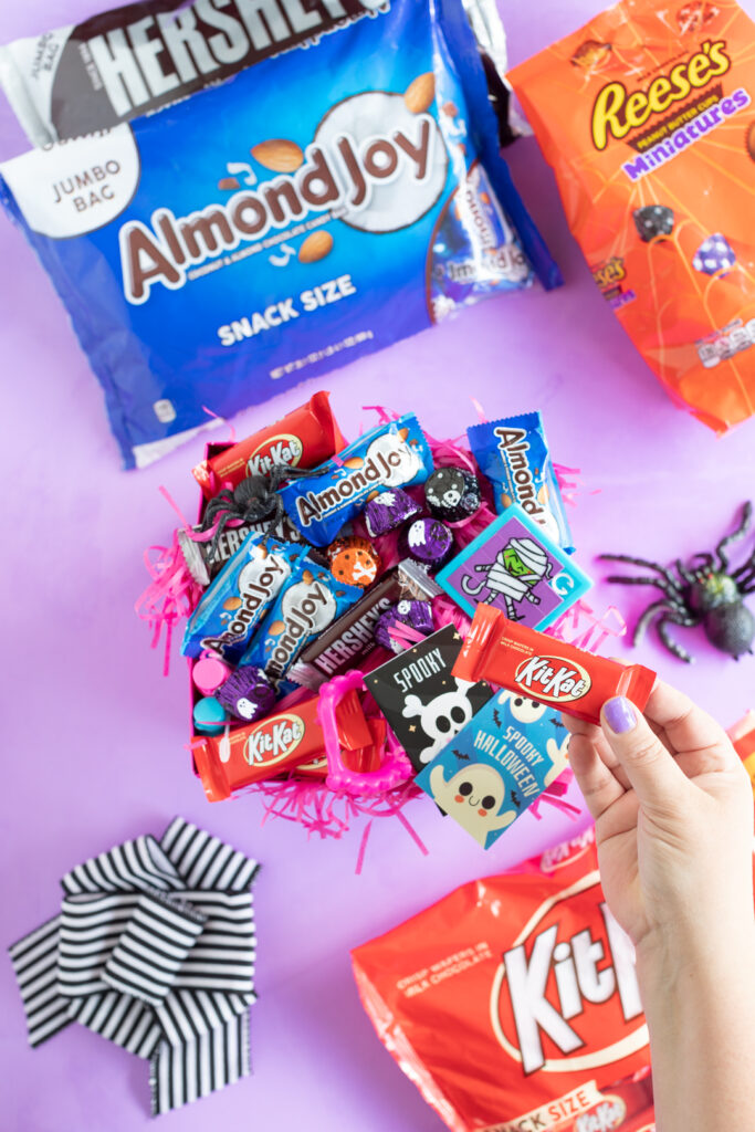adding a kit kat to a halloween gift box with other hershey treats and halloween trinkets