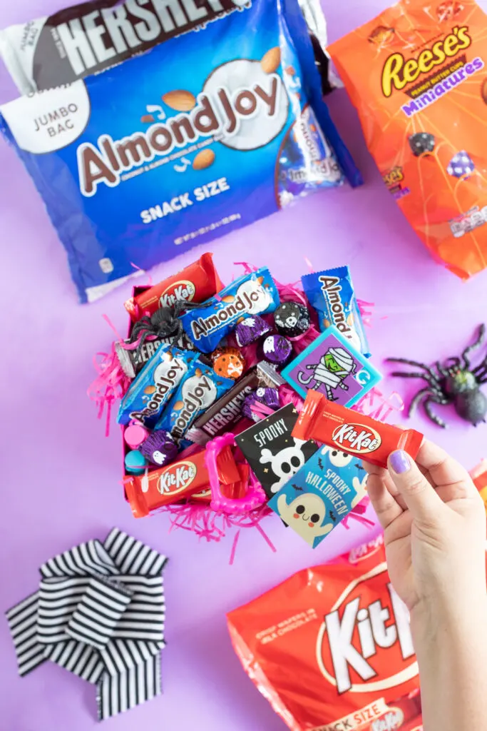 adding a kit kat to a halloween gift box with other hershey treats and halloween trinkets