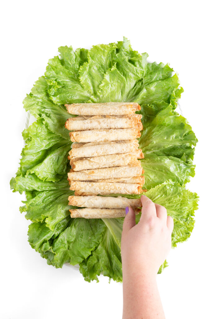 placing baked taquitos in the center of a bed of lettuce