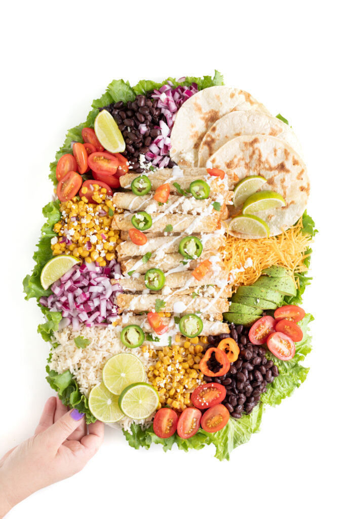 woman holding side of large platter of mexican inspired foods