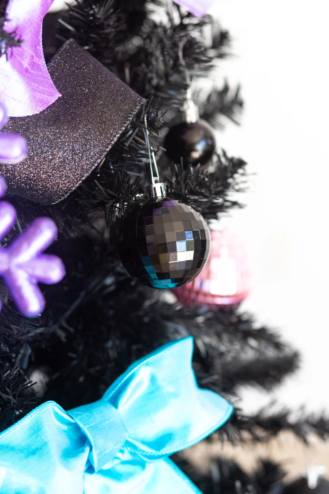 up close view of a shiny black christmas ornament hanging on a black christmas tree